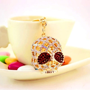Porte-clés crâne doré orné de strass blancs et yeux en cristal rouge sur tasse blanche