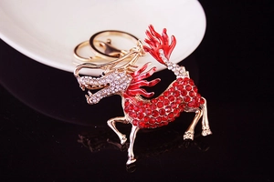 Macro view of gold Kirin keychain featuring vibrant red crystals and detailed metal craft