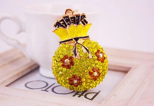Détail du porte-clés sac d'argent avec strass jaunes posé contre une tasse blanche