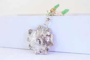 Close-up of silver metal flower keychain showing detailed texture and lobster clasp