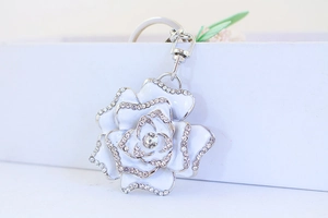 Macro detail of a rose keychain with white enamel petals and sparkling rhinestones