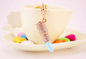 Détail du porte-clés rouge à lèvres en cristal avec pointe bleue sur une tasse