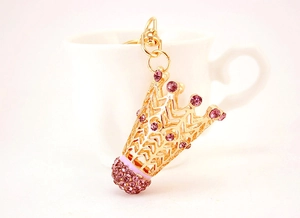 Détail d'un porte-clés couronne dorée avec strass violets suspendu à une tasse blanche