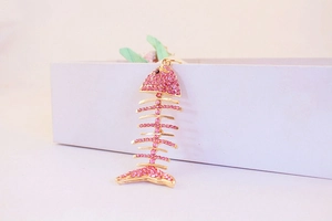 Détail du porte-clés arête de poisson en cristal rose et finition dorée sur coffret