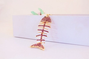Détail d'un porte-clés en forme d'arête de poisson avec strass violets et métal doré