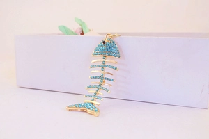 Détail d'un porte-clés en forme d'arête de poisson avec dorure et strass bleus