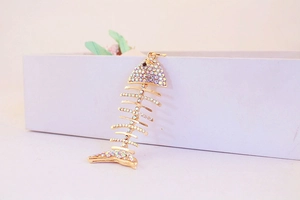 Gros plan du pendentif arête de poisson doré avec des strass colorés sur une boîte d'exposition