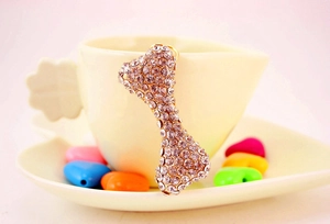 Detail of a sparkling crystal bone pendant hanging on a white coffee cup rim