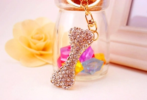 Detailed view of bone-shaped keychain featuring clear rhinestones and golden metal finish