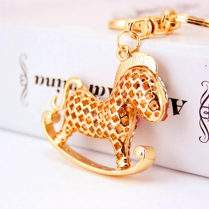 Porte-clés cheval à bascule doré avec strass et motifs de cœur posé sur un livre