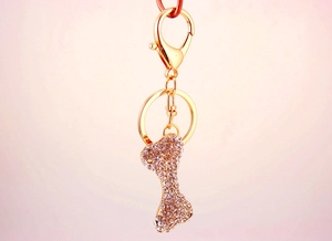 Detailed view of dog bone keychain with white rhinestones and lobster clasp on gold base