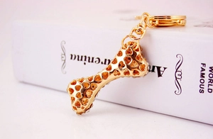 Detailed close-up of golden bone-shaped keychain with crystal-inlaid heart-cutout design