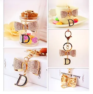 Détail du porte-clés nœud doré et lettre D avec incrustations de strass brillants