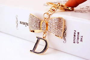 Détail d'un porte-clés à nœud en strass étincelants avec un pendentif noir lettre D