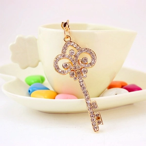 Porte-clés clé doré élégant avec strass brillants posé sur une tasse de café