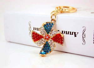 Detailed view of windmill keychain with sparkling red and blue rhinestones on gold metal