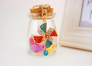 Detail of a sparkling rhinestone windmill keychain with blue crystal on a glass bottle