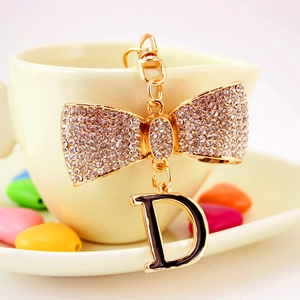 Porte-clés nœud en strass avec pendentif lettre D sur une tasse de café beige