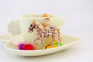 Vue détaillée d'un porte-clés cheval doré avec émail blanc et strass brillants étincelants