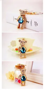 Three lifestyle shots of a gold teddy bear keychain with white diamonds and a blue gemstone