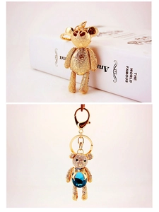 Macro detail of golden crystal bear keychain featuring a teardrop blue gemstone