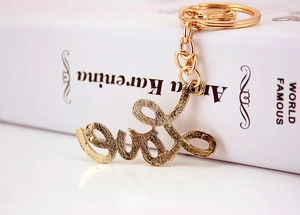 Macro side view of golden Love letter keychain leaning on a white classic book