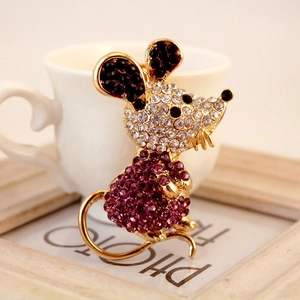 Exquisite gold-tone mouse keychain pendant with purple and white crystals on a white mug