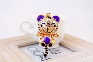 Détail du porte-clés tigre en métal doré avec strass brillants et finitions en émail violet