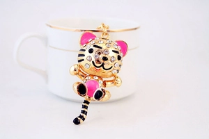 Détail d'un porte-clés tigre doré orné de strass blancs et d'émail rose brillant