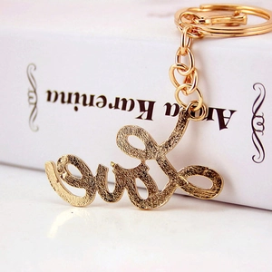 Golden rhinestone letter Love keychain with cursive cursive font and split ring on book