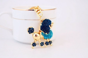Détail d'un porte-clés caniche créatif avec des strass bleus étincelants sur métal doré