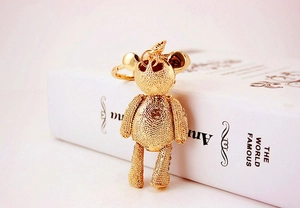 Close-up of golden metal bear keychain with textured hollow design and movable limbs