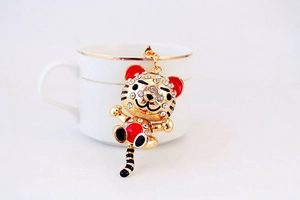 Détail d'un porte-clés tigre doré avec cristaux et émail rouge sur une tasse à café
