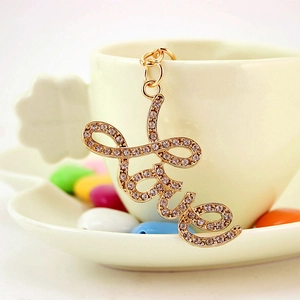 Golden rhinestone-studded Love keychain accessory displayed on a white ceramic cup