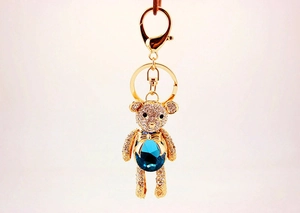 Detail of crystal bear keychain featuring a blue teardrop gemstone and white rhinestones