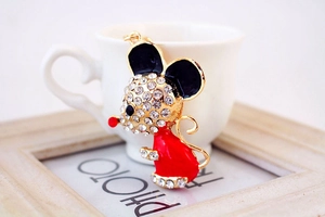 Detail of a golden zodiac mouse keychain with red enamel and sparkling crystal inlay