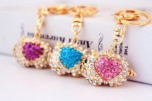 Detailed view of pig-shaped rhinestone keychains in pink, blue, and purple colors