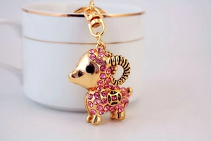 Détail d'un porte-clés chèvre dorée avec strass roses accroché sur une tasse à café