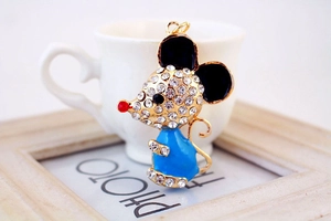 Detail of a golden mouse pendant with blue enamel, white rhinestones and a red nose charm