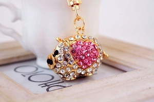 Macro detail of gold pig keychain with pink crystal heart and sparkling rhinestones