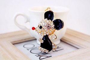 Detail of a gold-plated mouse pendant with black enamel and sparkling white rhinestones