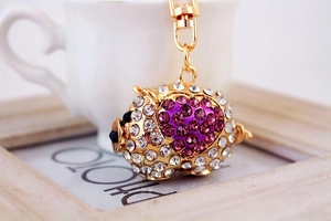 Macro shot of pig keychain showing sparkling crystals and gold plating on white surface