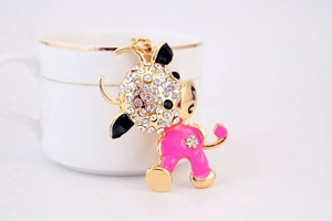 Macro di un portachiavi a forma di bue in smalto rosa con strass accanto a una tazza