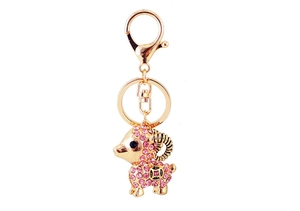 Détail de porte-clés chèvre dorée avec cristaux roses et motif de pièce chinoise
