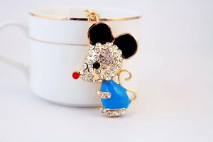 Detailed macro shot of a crystal-studded mouse keychain charm by a white coffee cup