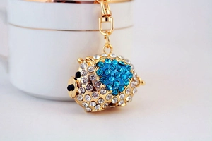 Detail showing blue and white rhinestones on a golden pig keychain with lobster clasp