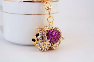 Close-up of golden pig keychain with sparkling white and purple rhinestones