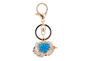 Detail of pig keychain with sparkling blue and white crystals on polished gold metal hardware