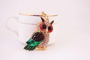 Detail of owl keychain with sparkling rhinestones and green enamel on a golden base
