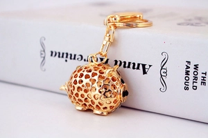 Detailed close-up of golden hollow pig keychain with heart-shaped crystal embellishments